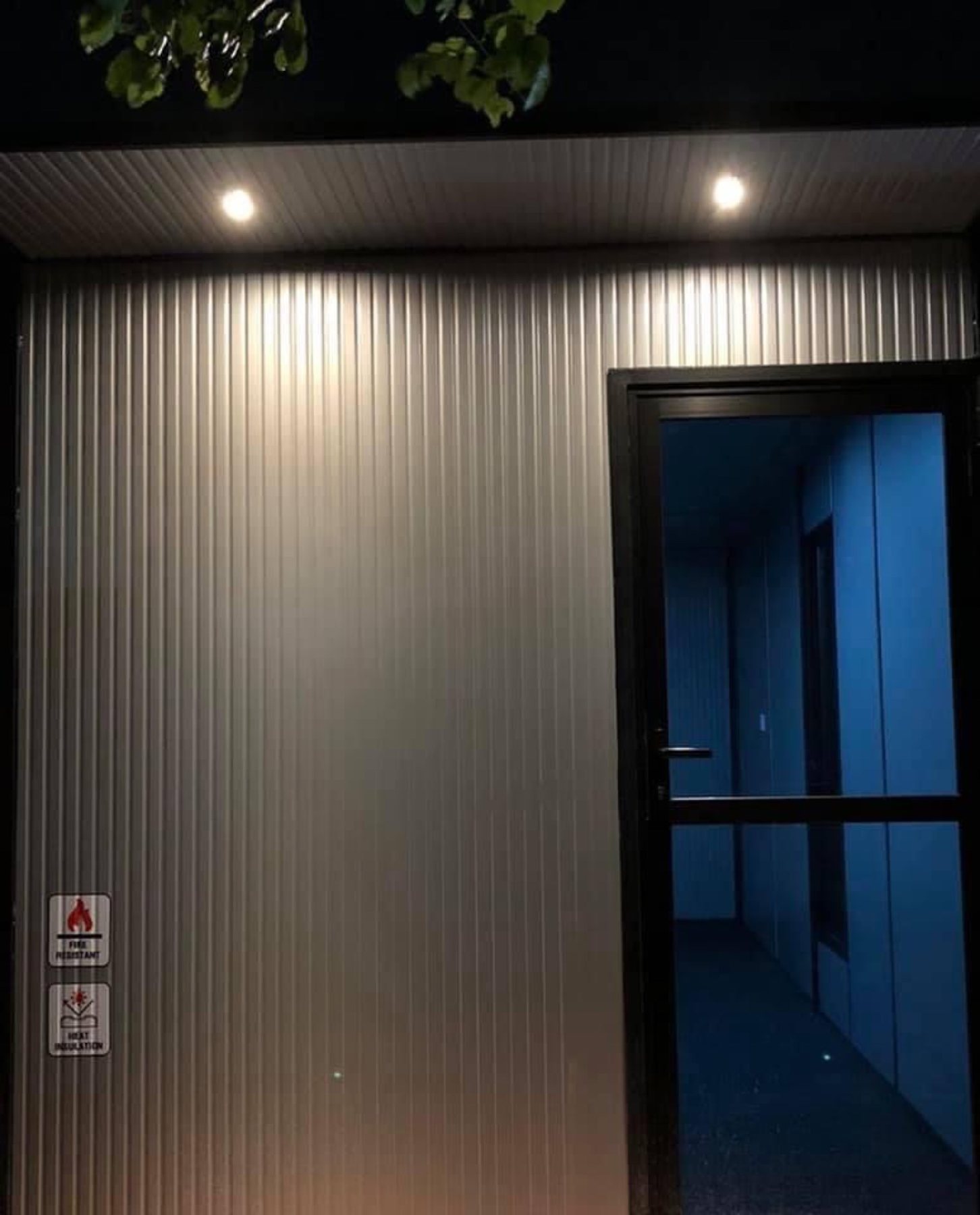 Ribbed steel corridor inside a container unit, downlit