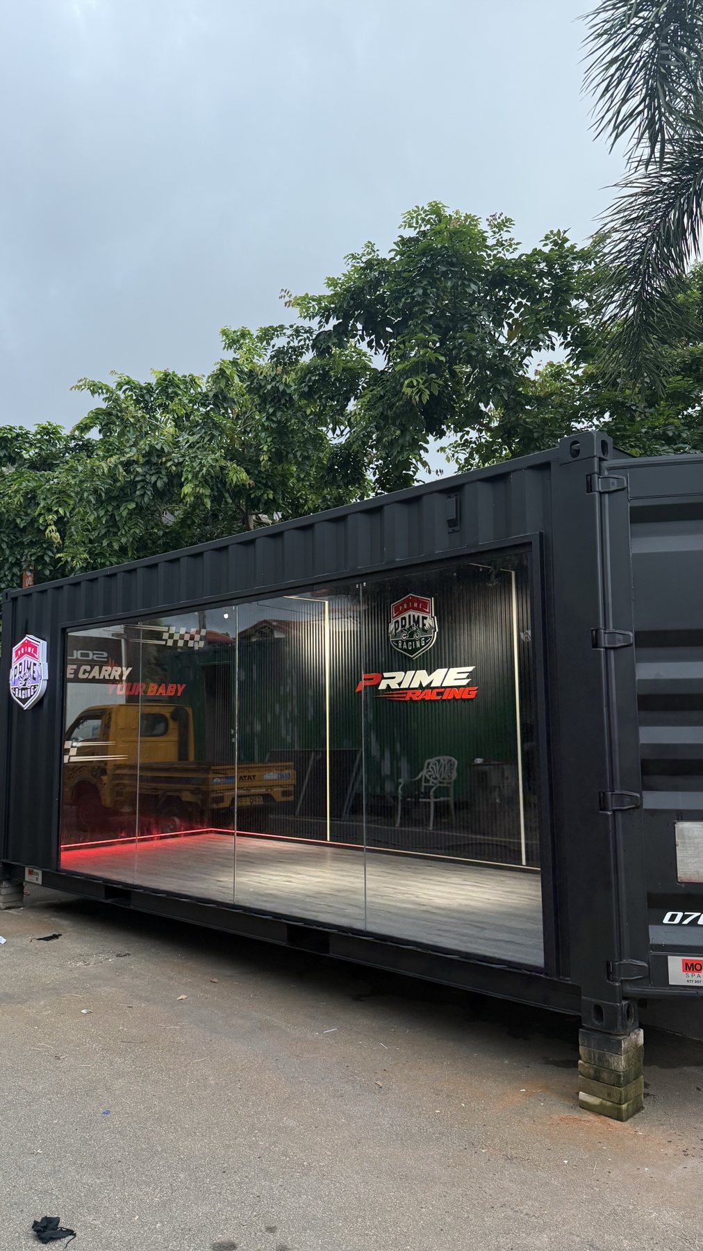 Prime Racing motorcycle showroom built from a black shipping container, glass front and red interior light