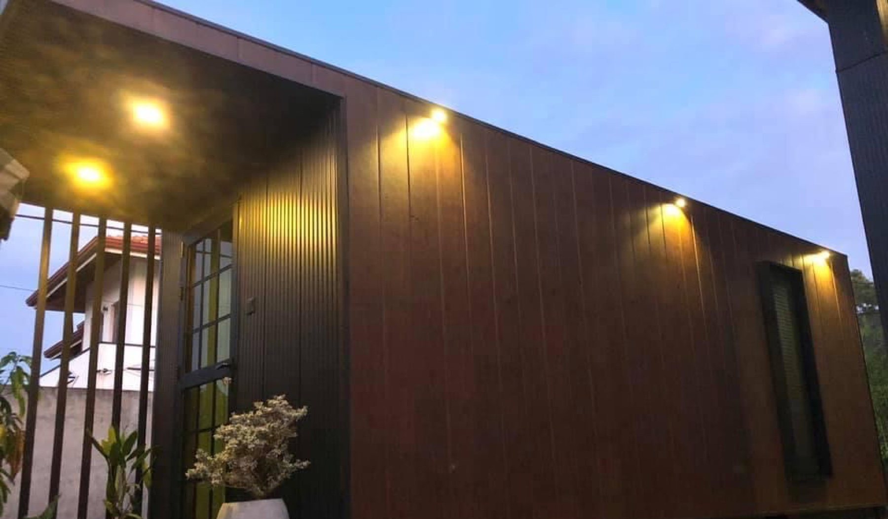 Timber-clad modular office unit by Modern Space, lit at dusk